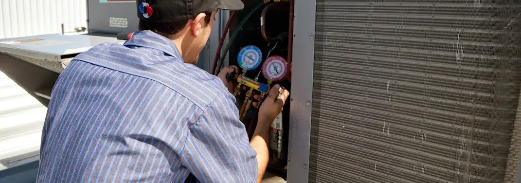 HVAC technician servicing a condenser unit in Carver
